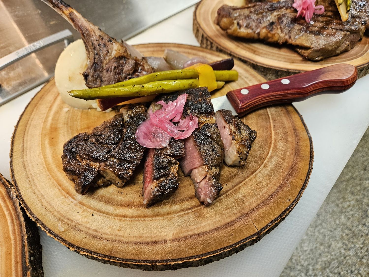 Sliced steak on a round wooden board with grilled asparagus