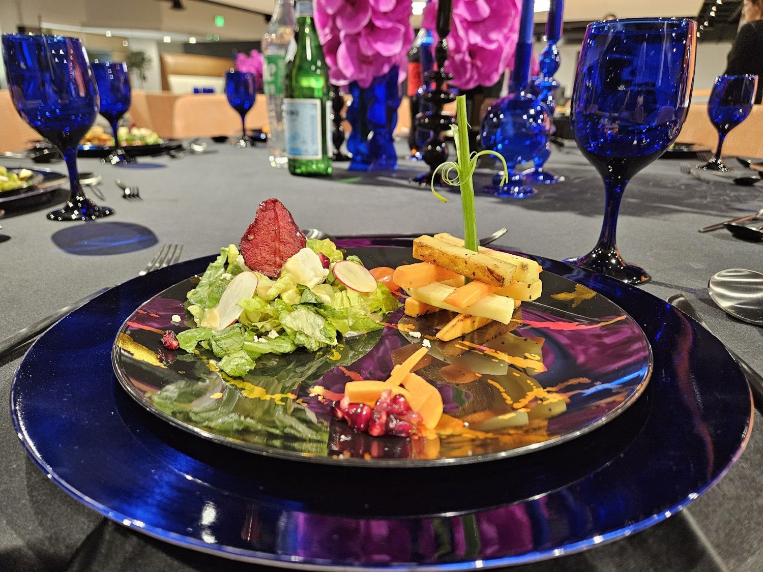 Salad on a blue glass charger at a set banquet table